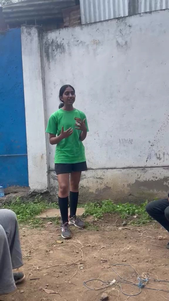 A student holding up a planted bottle while talking to a seated group